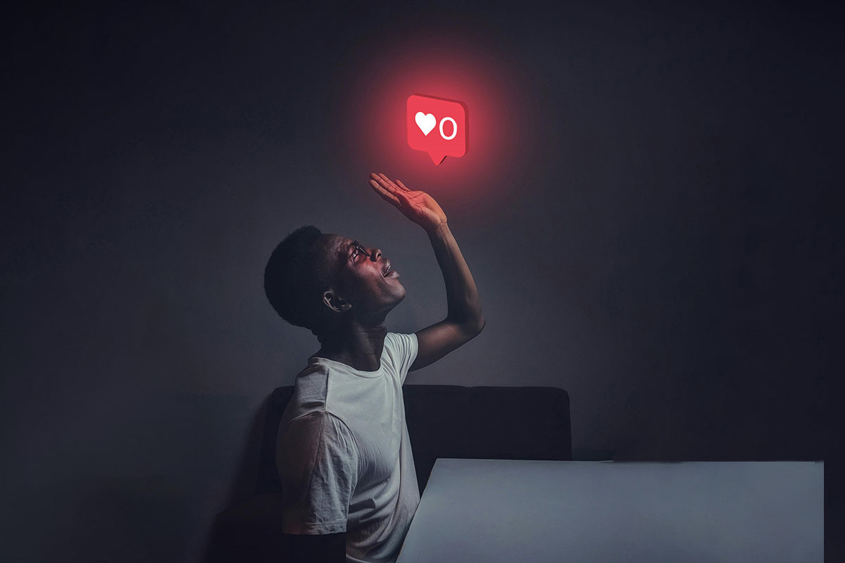 A person in a dark room looks up at a glowing social media 